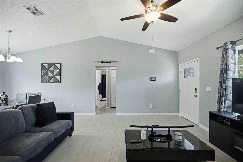A living room features light gray walls, tile flooring, a vaulted ceiling, and a ceiling fan — 17725 SW 31ST AVENUE, OCALA, FL
