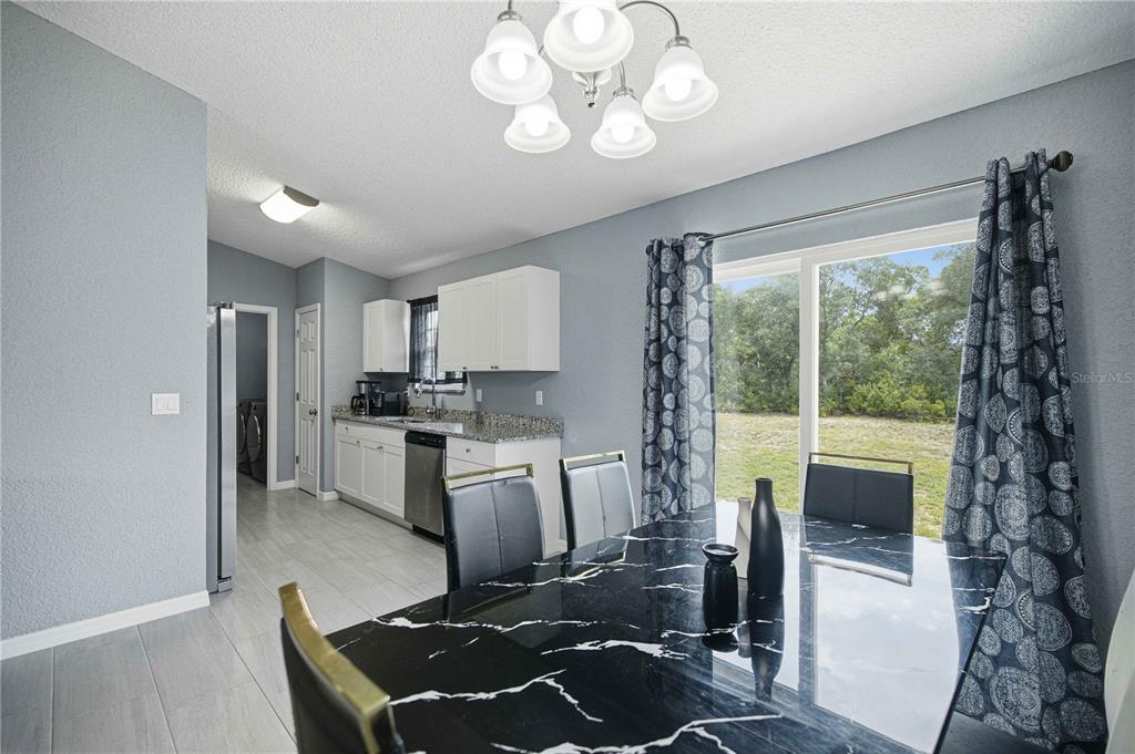 A dining area with a black marble table sits adjacent to a kitchen with white cabinets — 17725 SW 31ST AVENUE, OCALA, FL