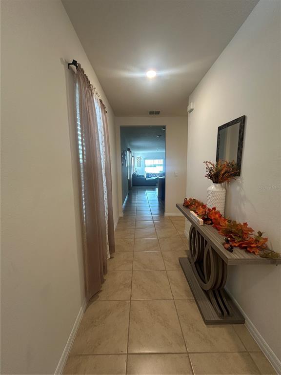 A hallway with tile flooring, a console table, and a view into a living area — 1396 BERRY LANE, DAVENPORT, FL