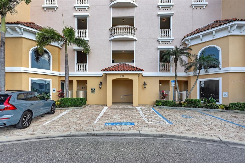 A multi-story building exterior features a covered entrance, palm trees, and a paved parking area — 205 BRIGHTWATER DRIVE UNIT 202, CLEARWATER BEACH, FL