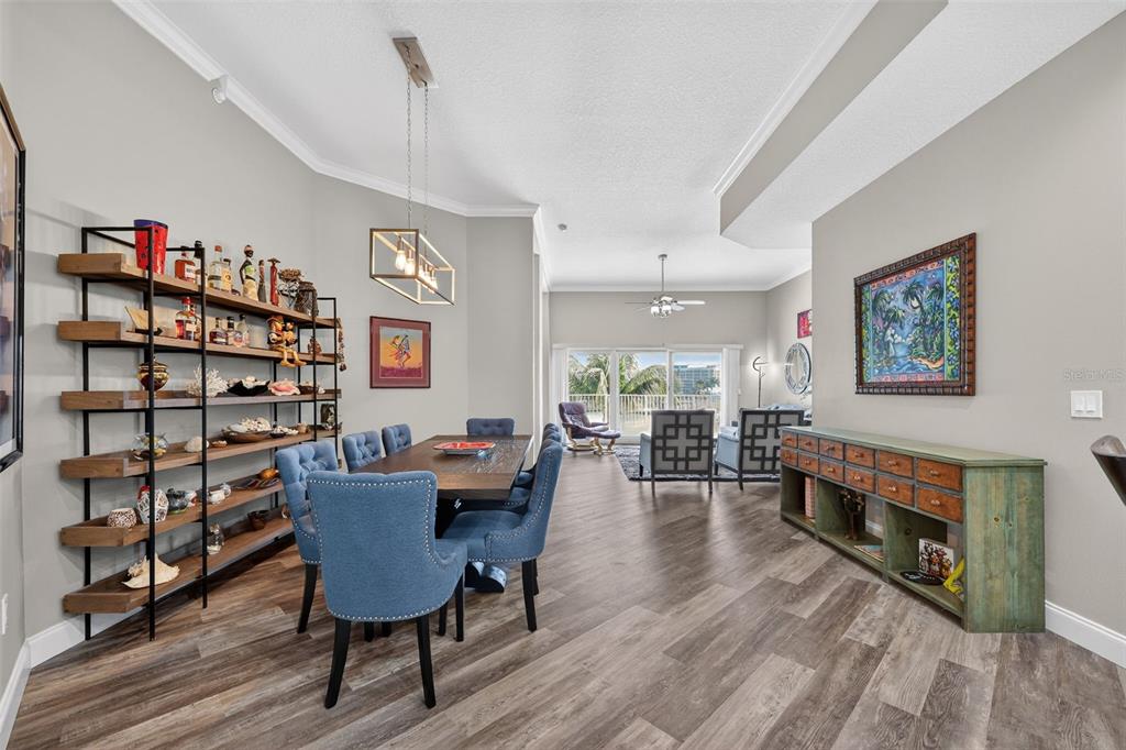 A dining room with a wooden table, blue chairs, open shelving, and a green sideboard — 205 BRIGHTWATER DRIVE UNIT 202, CLEARWATER BEACH, FL