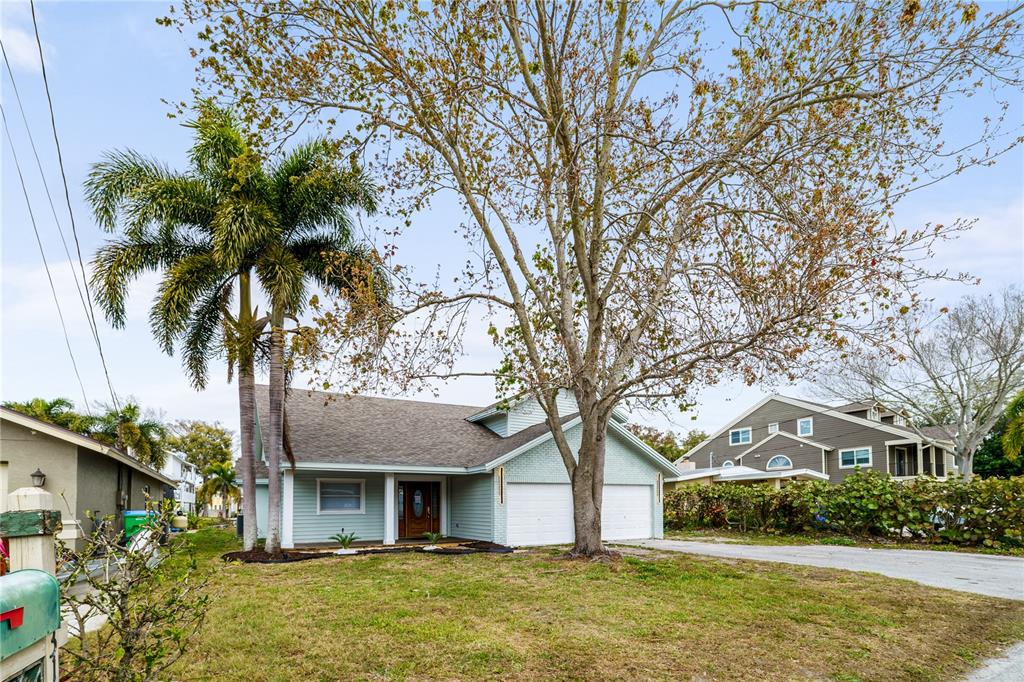 A light blue house with a two-car garage, a palm tree, and a large tree — 3149 N CANAL DRIVE, PALM HARBOR, FL