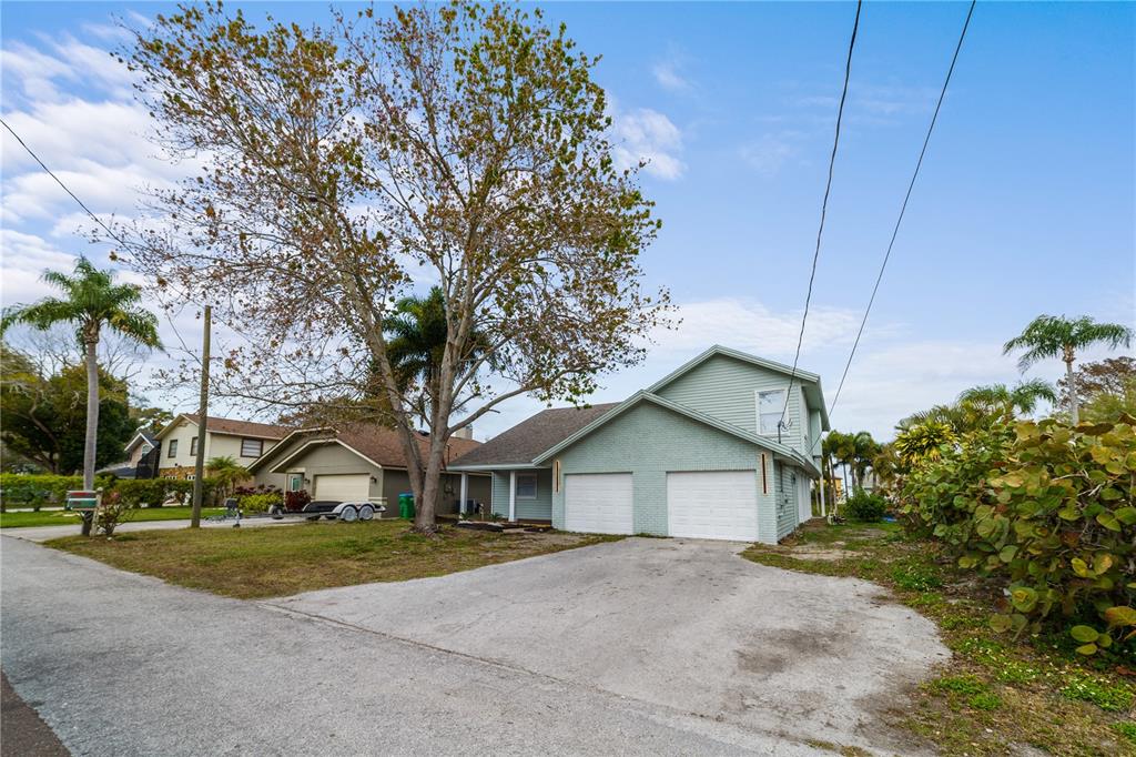 A light green two-story house features a two-car garage and a large tree in front — 3149 N CANAL DRIVE, PALM HARBOR, FL