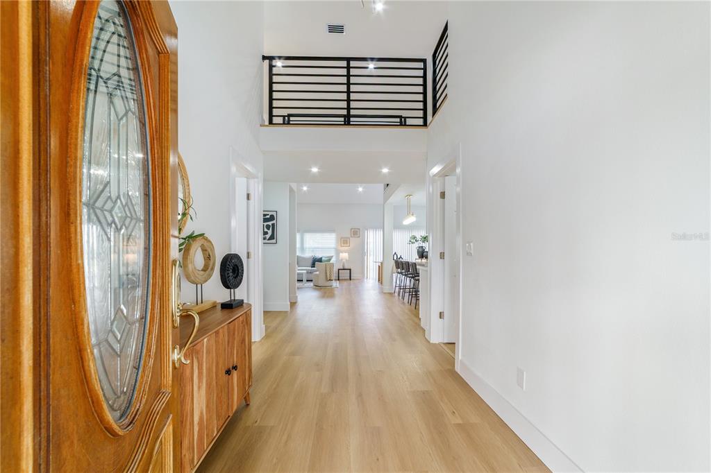 A bright entryway leads into an open-concept living area with light wood flooring — 3149 N CANAL DRIVE, PALM HARBOR, FL