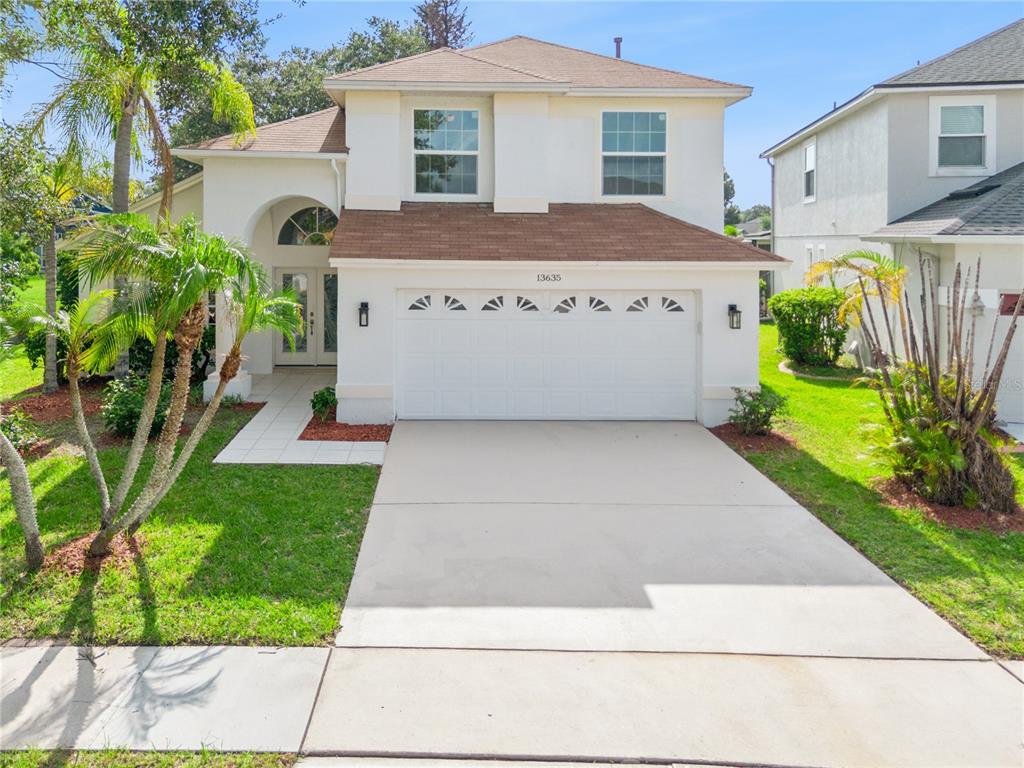 A two-story house with a white stucco exterior, brown roof, and a two-car garage — 13635 WATERHOUSE WAY, ORLANDO, FL