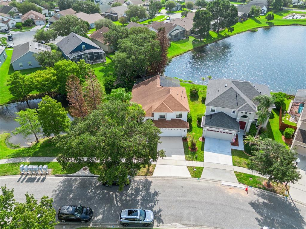 An aerial view shows two suburban houses with driveways situated next to a small lake — 13635 WATERHOUSE WAY, ORLANDO, FL