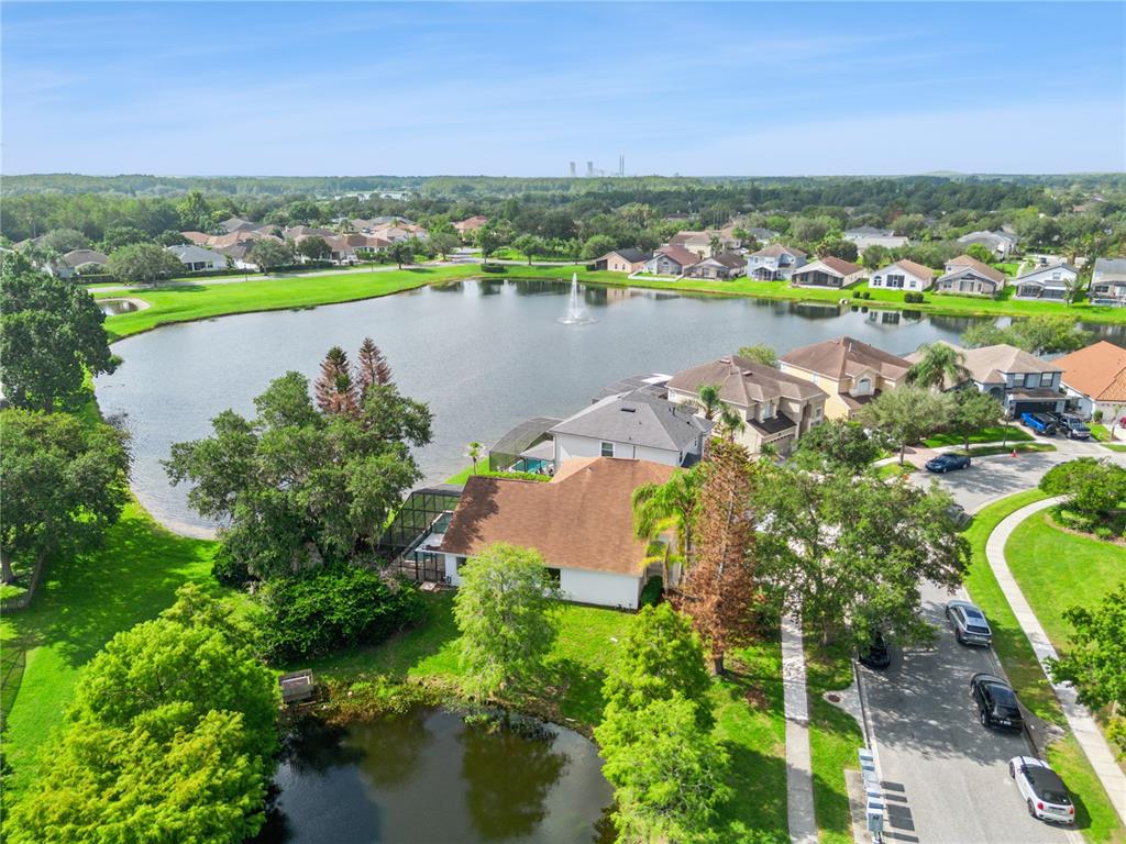 An aerial view shows a suburban house with a pool cage beside a large pond — 13635 WATERHOUSE WAY, ORLANDO, FL