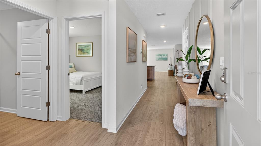 A hallway with wood-look flooring leads to a bedroom and an open living area — 72 SAWDUST LANE, PALM COAST, FL