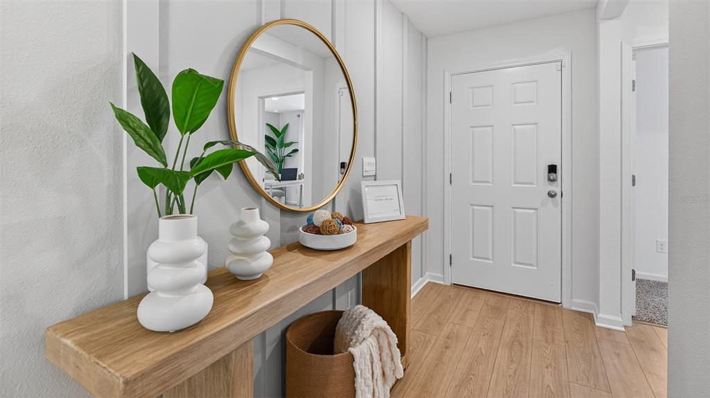 A modern entryway features a wooden console table, a round gold mirror, and white walls — 72 SAWDUST LANE, PALM COAST, FL