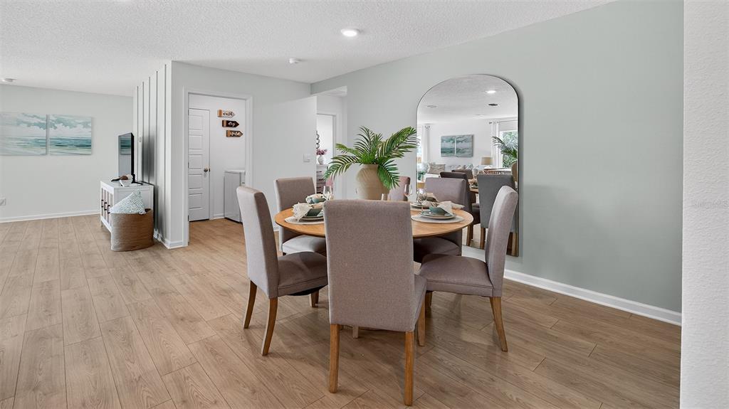 A dining area features a round wooden table, four upholstered chairs, and a large arched mirror — 72 SAWDUST LANE, PALM COAST, FL