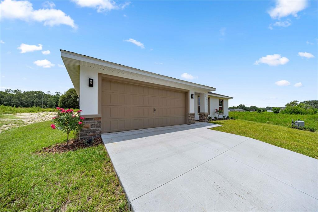 An open-concept living and kitchen area features light wood-look flooring and a vaulted ceiling — 14810 SW 33RD LANE, OCALA, FL
