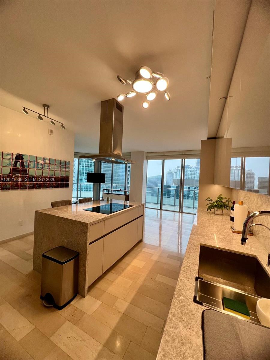 A balcony with outdoor furniture overlooks a bay and a neighboring high-rise building — 1300 E Brickell Bay Dr # 3701, Miami FL 33131, MIAMI, FL