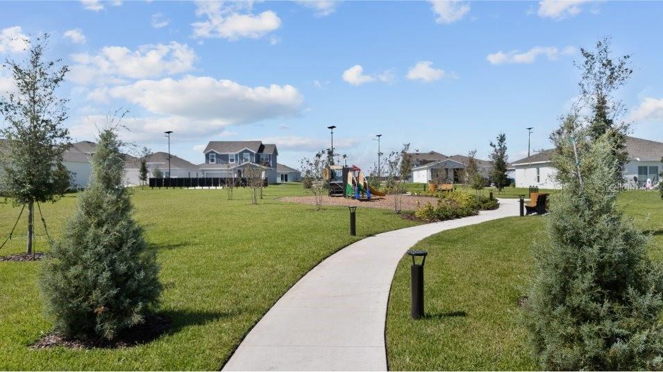 A concrete path leads through a grassy park toward a playground and residential houses — 2202 LASSO LOOP, EAGLE LAKE, FL