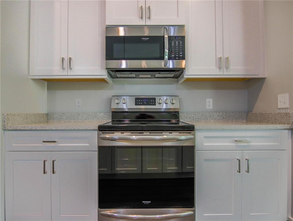 A kitchen features white cabinets, stainless steel appliances, and a speckled granite countertop — 525 SW HEATHRIDGE DRIVE, LAKE CITY, FL