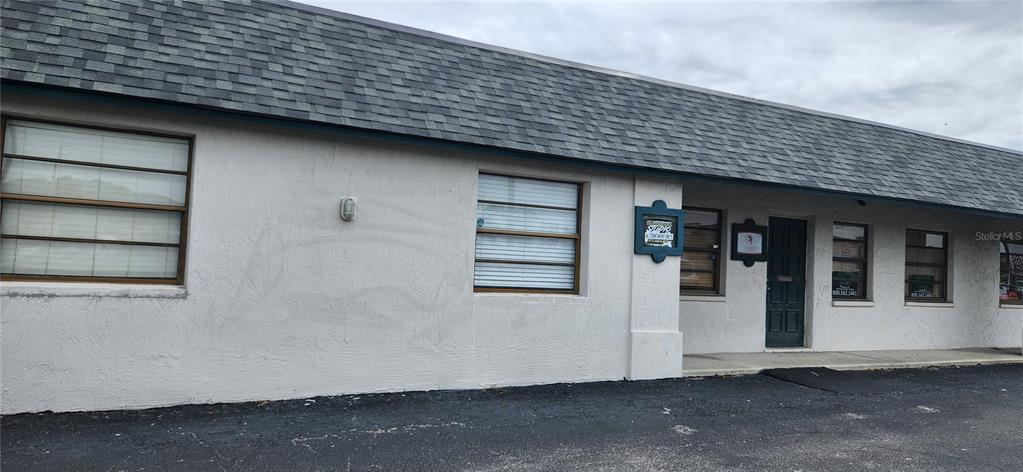 A single-story commercial building with a gray shingled roof and a paved parking lot — 6609 RIDGE ROAD UNIT 1, PORT RICHEY, FL