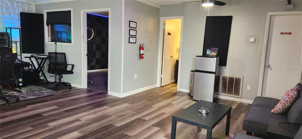 A room with wood-look flooring, a small refrigerator, a coffee table, and a sofa — 6609 RIDGE ROAD UNIT 1, PORT RICHEY, FL