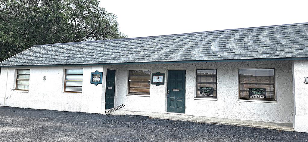 A single-story commercial building with a gray shingled roof and white stucco exterior walls — 6609 RIDGE ROAD UNIT 1, PORT RICHEY, FL