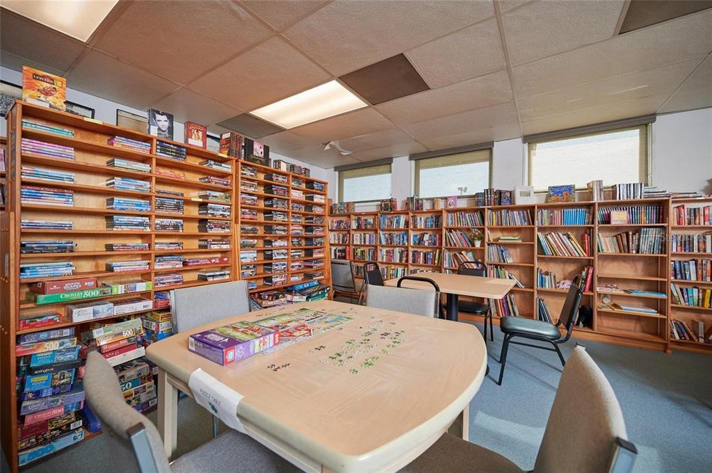 A room filled with bookshelves, puzzle boxes, and tables with chairs on a carpeted floor — 0 LAGUNA DRIVE, INDIAN LAKE ESTATES, FL