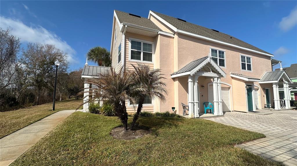 A two-story tan townhouse with a metal-roofed entryway and a small palm tree outside — 5006 MANGROVE ALLEY UNIT 201, KISSIMMEE, FL