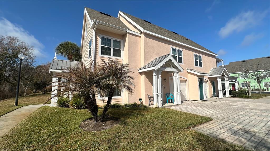 A two-story peach-colored townhouse with a palm tree in the front yard — 5006 MANGROVE ALLEY UNIT 201, KISSIMMEE, FL