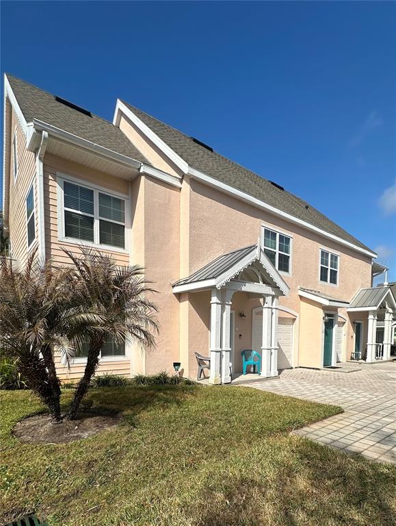 A two-story peach-colored townhouse with a gabled roof and a small front porch — 5006 MANGROVE ALLEY UNIT 201, KISSIMMEE, FL