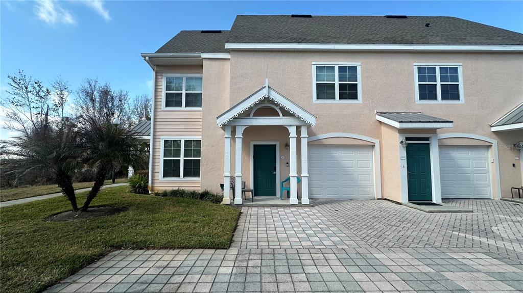 A two-story townhouse with a peach stucco exterior, a paved driveway, and a covered entryway — 5006 MANGROVE ALLEY UNIT 201, KISSIMMEE, FL