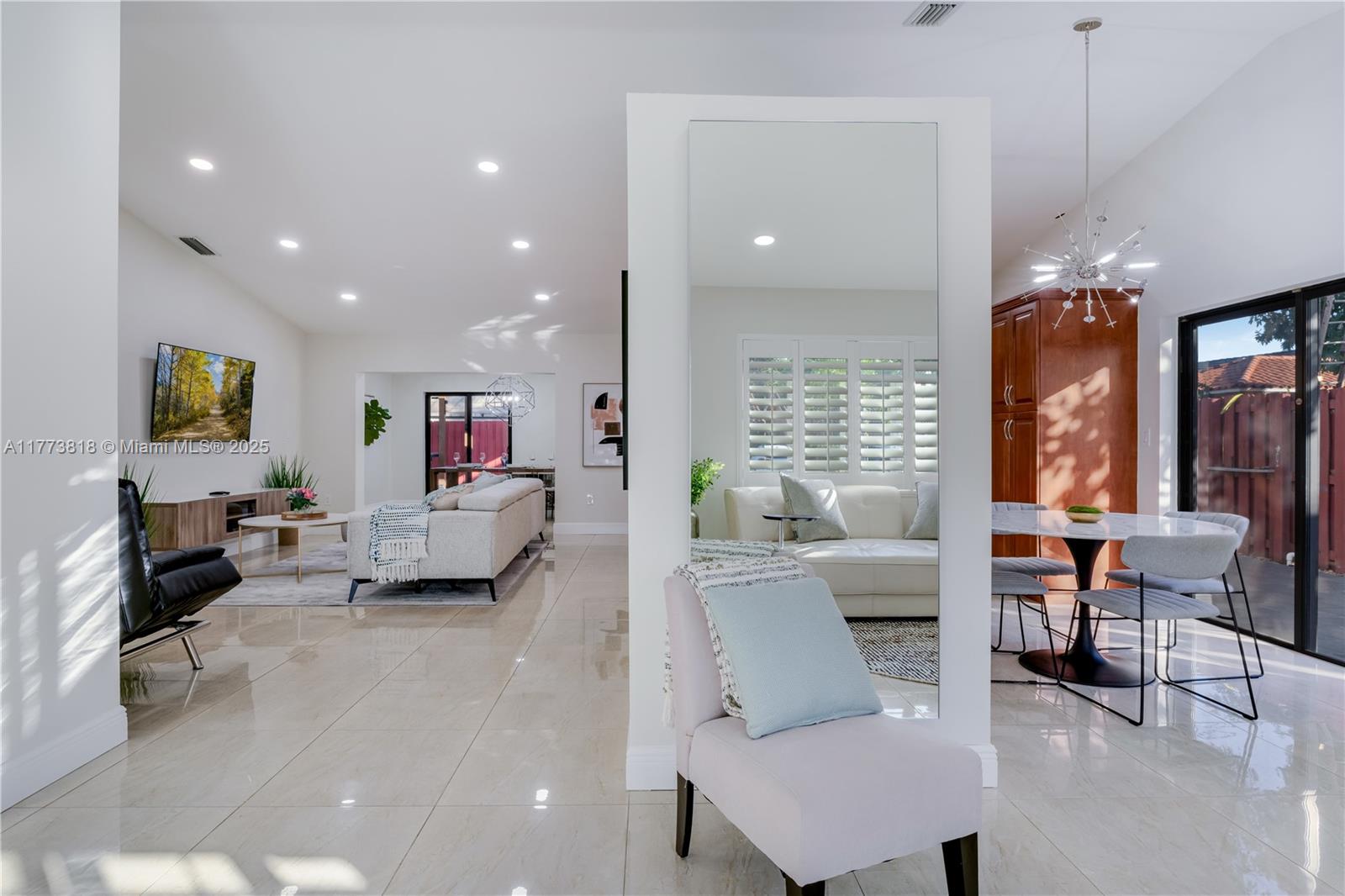 An open-concept living and dining area features tile floors, a central mirror, and modern furniture — 14517 SW 98th Ter, Miami FL 33186, MIAMI, FL