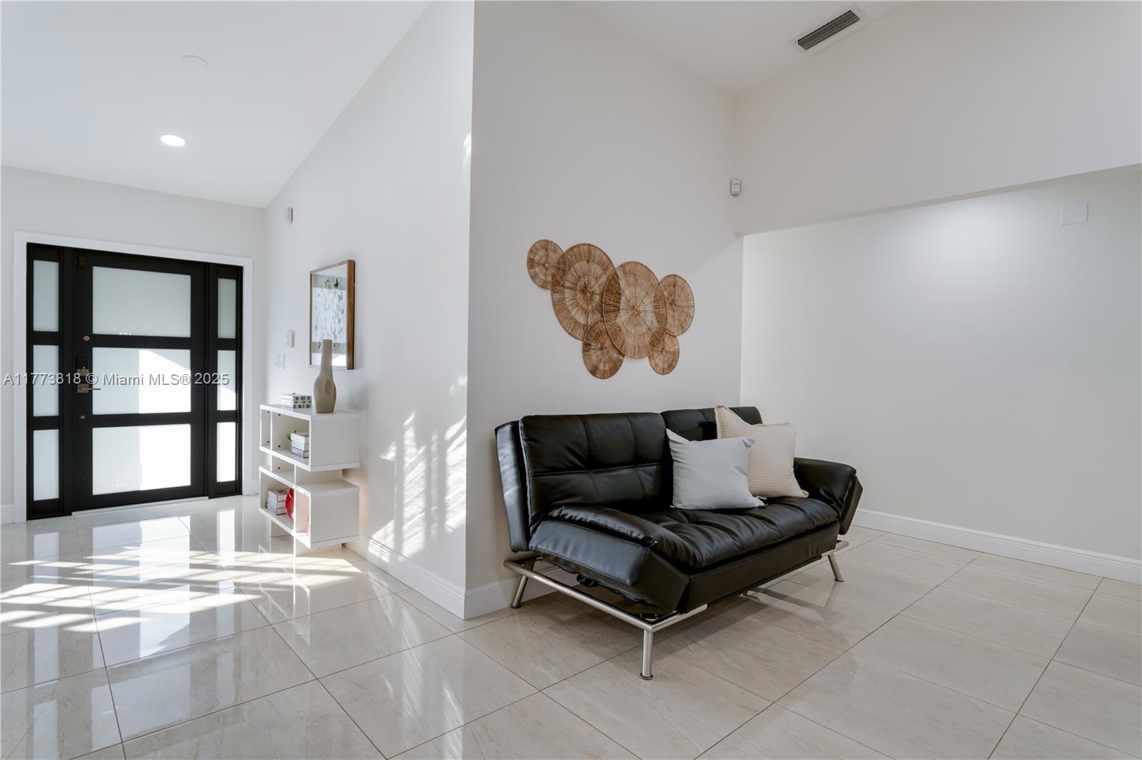 A bright entryway features white walls, tiled floors, a black sofa, and a modern front door — 14517 SW 98th Ter, Miami FL 33186, MIAMI, FL