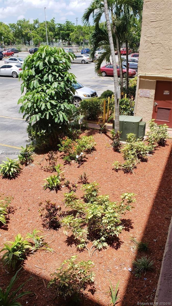 An elevated view of a landscaped garden bed with mulch and shrubs beside a building — 1325 W 68th St # 214, Hialeah FL 33014, HIALEAH, FL