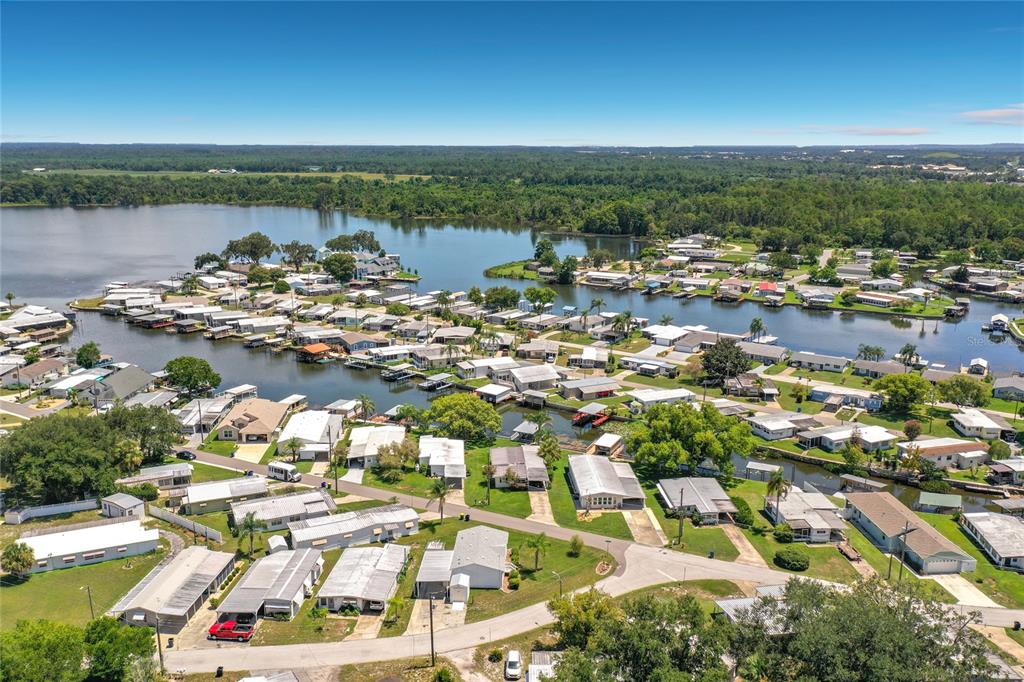An aerial view shows a waterfront mobile home community with docks and surrounding green space — 1521 LAKEVIEW DRIVE, TAVARES, FL