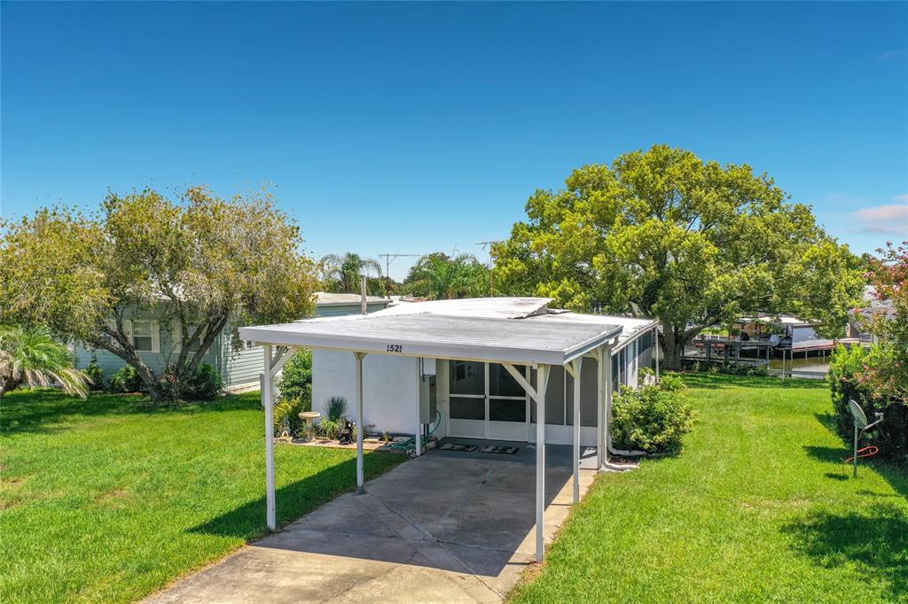 A single-story house with a white exterior, a carport, and a screened-in front porch — 1521 LAKEVIEW DRIVE, TAVARES, FL