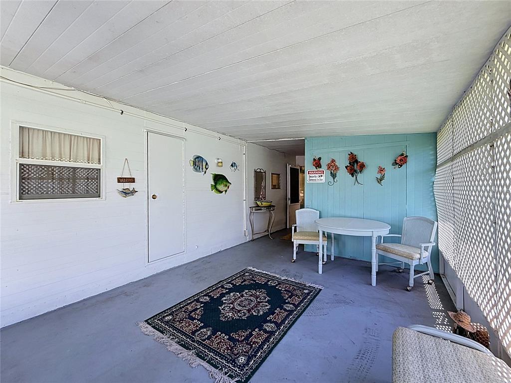 A covered porch features a concrete floor, white walls, a lattice screen, and patio furniture — 1521 LAKEVIEW DRIVE, TAVARES, FL