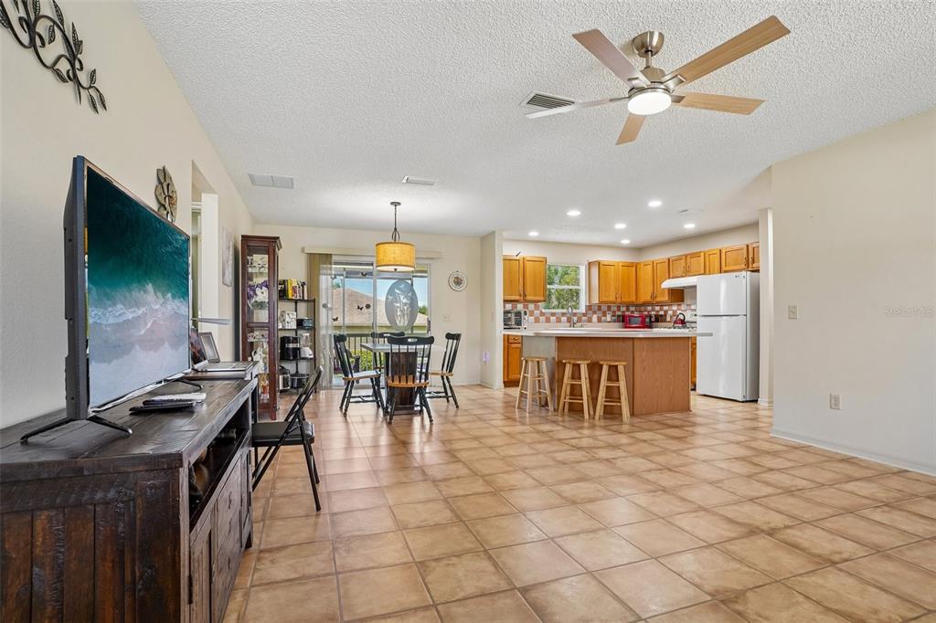 An open-concept kitchen and dining area features tile flooring, wood cabinetry, and a ceiling fan — 970 KENOVA AVENUE, THE VILLAGES, FL