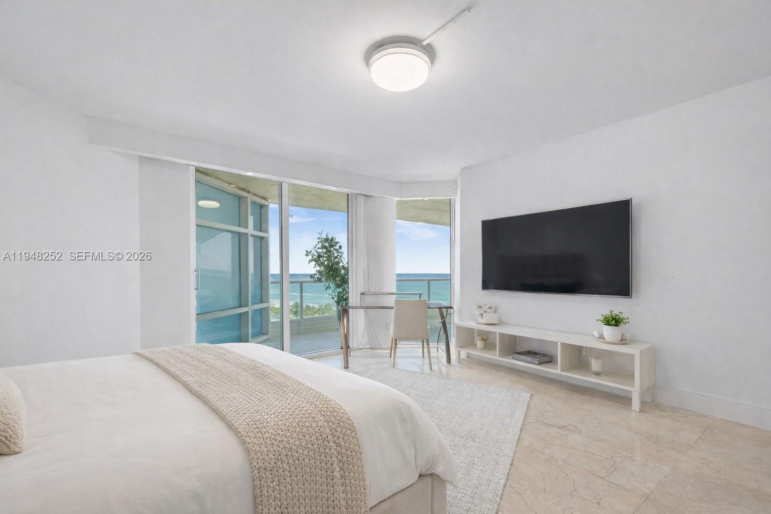 A bedroom features a bed, a desk by the window, and a wall-mounted television — 5025 Collins Ave # 903, Miami Beach FL 33140, MIAMI BEACH, FL