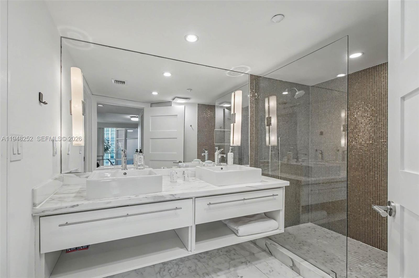 A modern bathroom features a double vanity with vessel sinks, marble countertops, and a glass-enclosed shower — 5025 Collins Ave # 903, Miami Beach FL 33140, MIAMI BEACH, FL