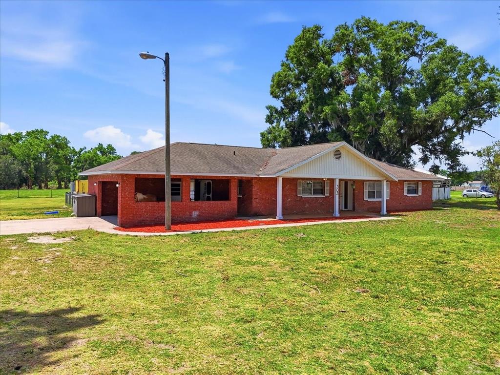 A single-story red brick house with a covered porch and a large tree nearby — 303 KARPPE ROAD, PLANT CITY, FL