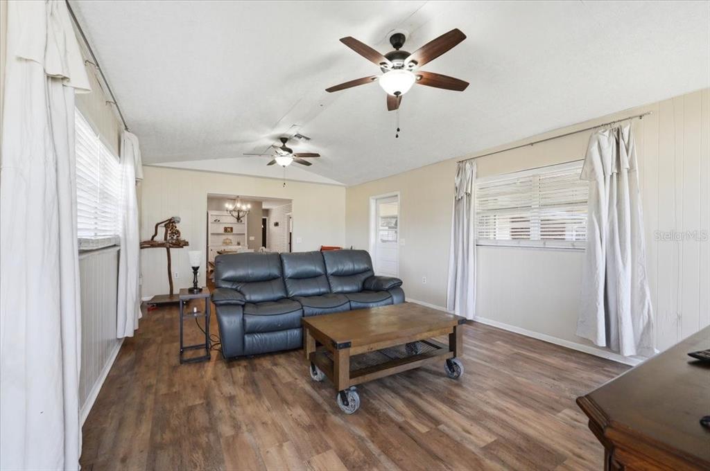 A living room features wood-look flooring, a dark leather sofa, and two ceiling fans — 303 KARPPE ROAD, PLANT CITY, FL