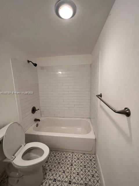 A bathroom with a white tiled shower-tub combo, patterned floor tiles, and a toilet — 7001 Environ Blvd # 308, Lauderhill FL 33319, LAUDERHILL, FL