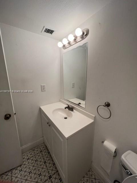 A small bathroom features a white vanity, a wall-mounted mirror, and patterned tile flooring — 7001 Environ Blvd # 308, Lauderhill FL 33319, LAUDERHILL, FL