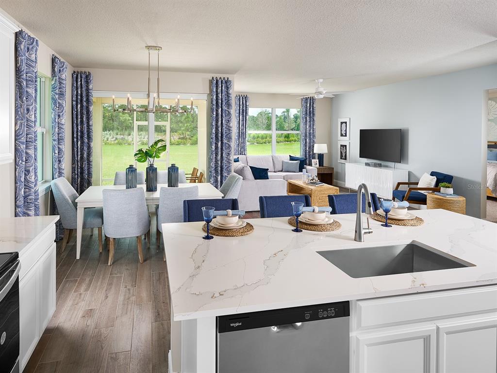 A kitchen island with a sink overlooks an open-concept dining area and living room — 392 BIRKDALE DRIVE, DAYTONA BEACH, FL