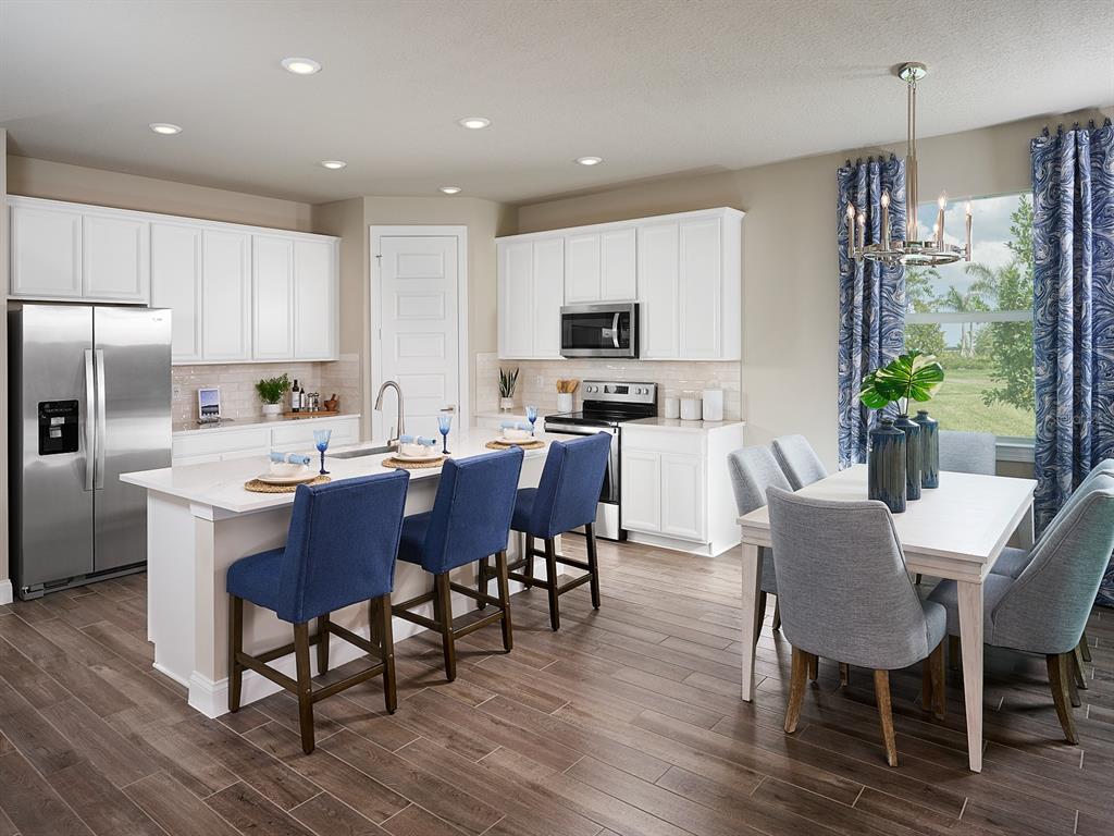 A kitchen with white cabinets, stainless steel appliances, a center island, and an adjacent dining area — 392 BIRKDALE DRIVE, DAYTONA BEACH, FL