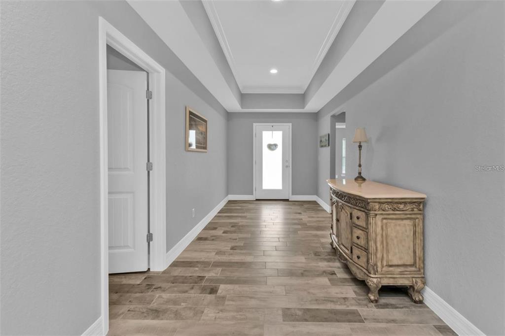 A bright entryway features gray walls, wood-look tile flooring, and a recessed tray ceiling — 14516 SAN DOMINGO BOULEVARD, PORT CHARLOTTE, FL