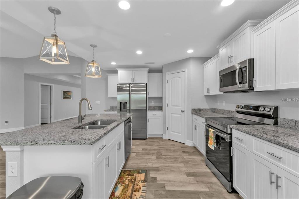 A kitchen featuring white cabinets, granite countertops, stainless steel appliances, and a central island — 14516 SAN DOMINGO BOULEVARD, PORT CHARLOTTE, FL