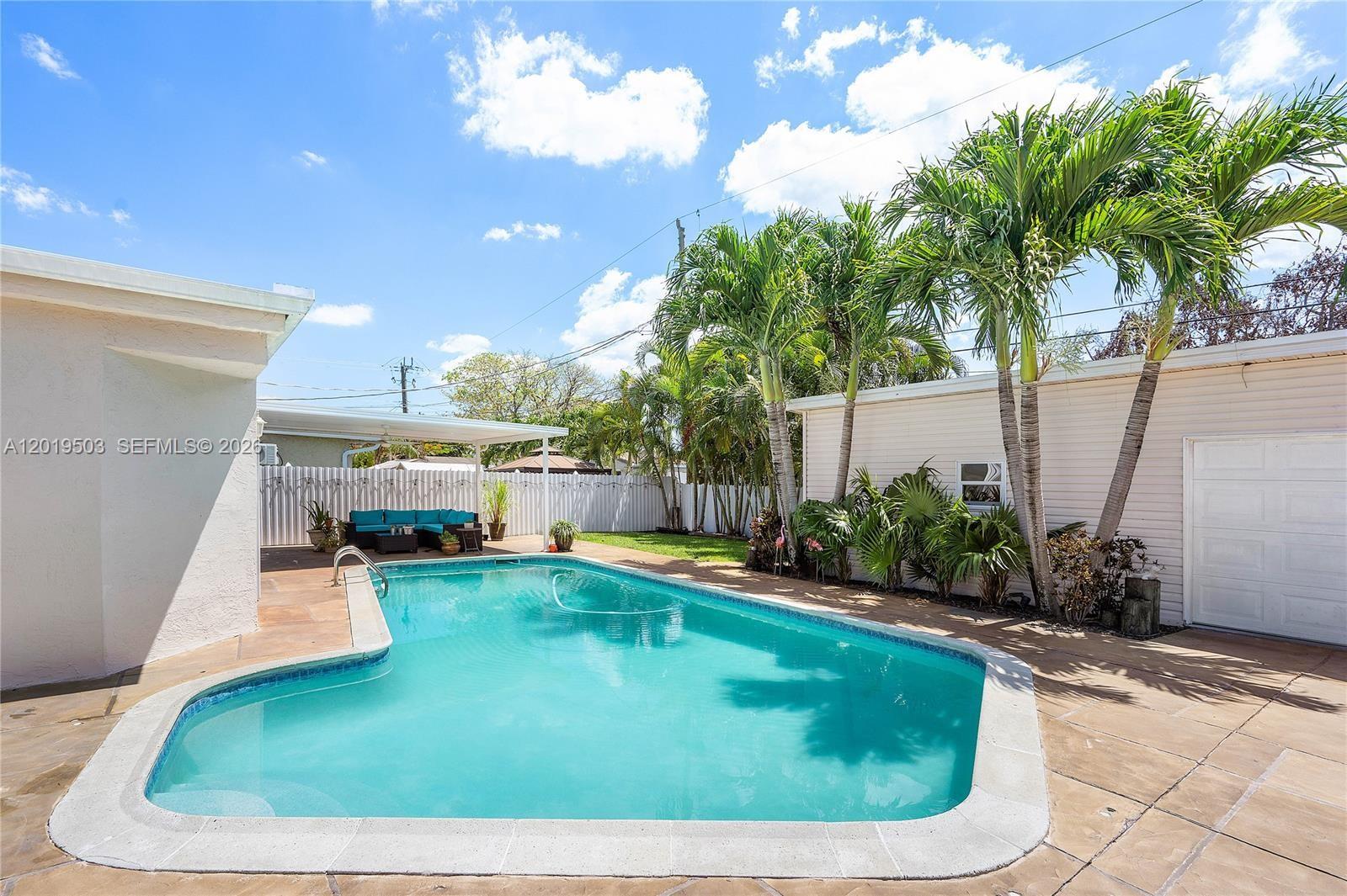 A backyard features a swimming pool, a covered patio area, and several palm trees — 3021 N 72nd Way, Hollywood FL 33024, HOLLYWOOD, FL