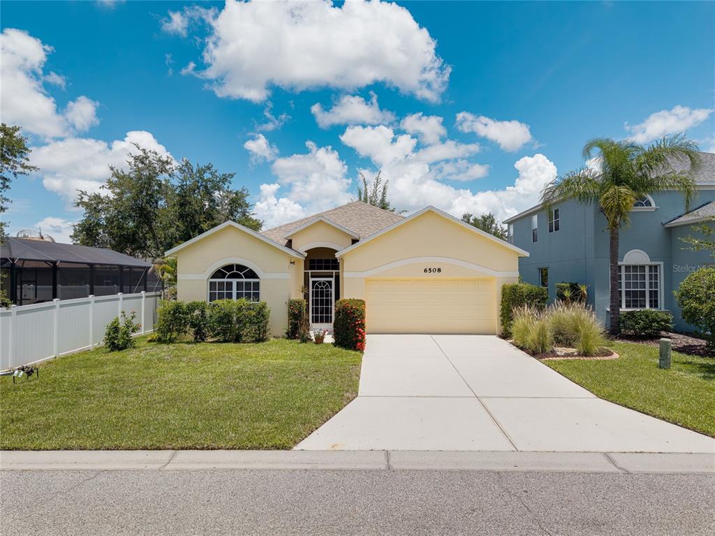 A single-story yellow house with a two-car garage and a concrete driveway — 6508 ROCK BRIDGE LANE, ELLENTON, FL