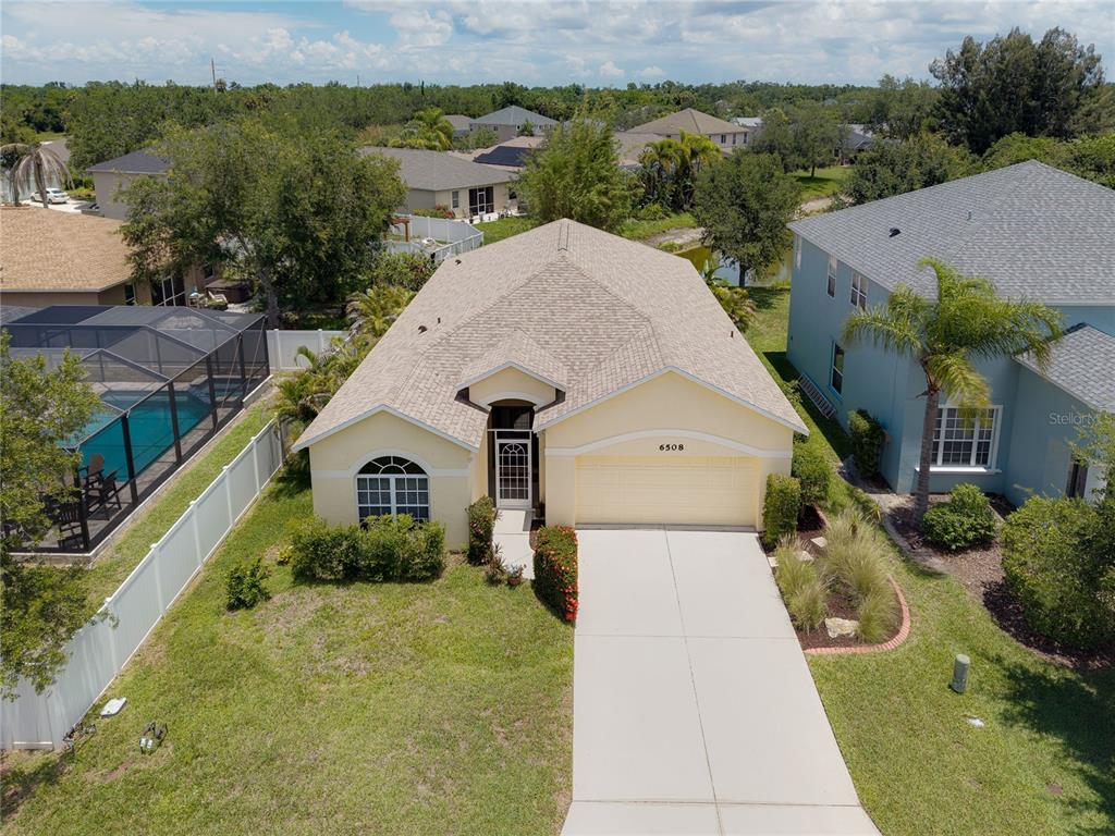 An aerial view shows a single-story house with a tan roof and a concrete driveway — 6508 ROCK BRIDGE LANE, ELLENTON, FL