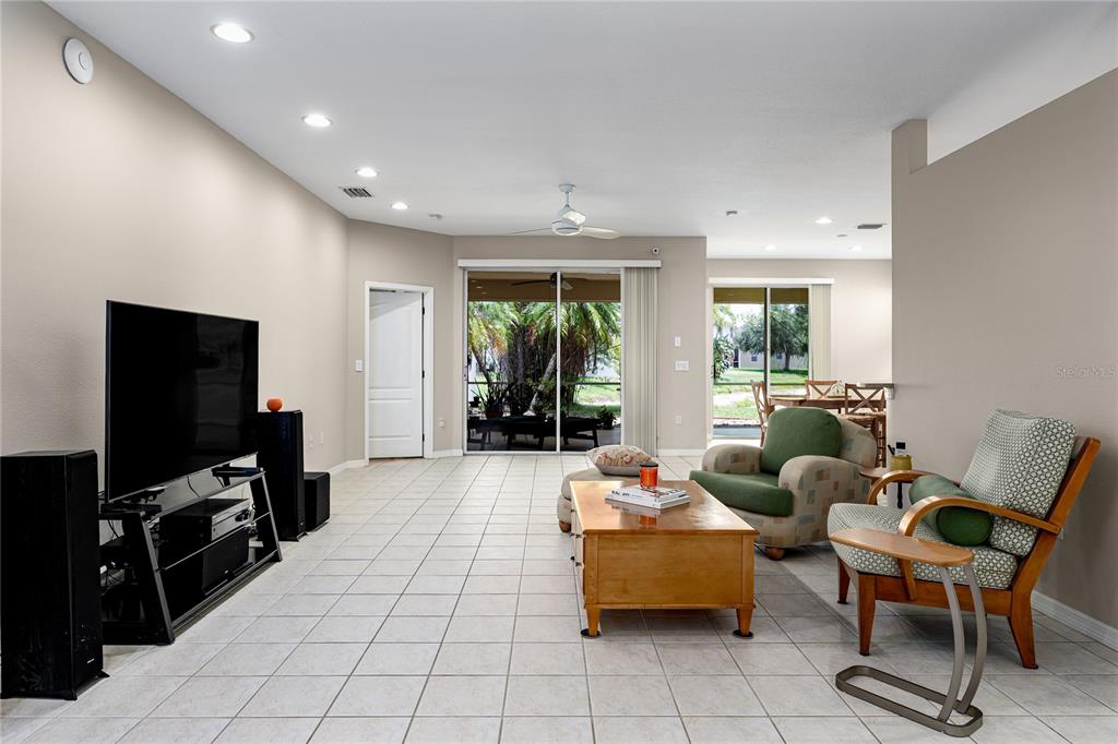 A living room with tile flooring, a television, a coffee table, and two armchairs — 6508 ROCK BRIDGE LANE, ELLENTON, FL