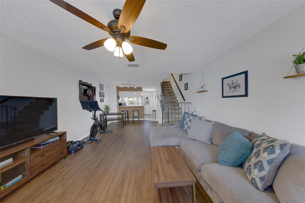 A living room features wood-look flooring, a sectional sofa, a television, and a ceiling fan — 3315 W WYOMING CIRCLE UNIT 3315, TAMPA, FL