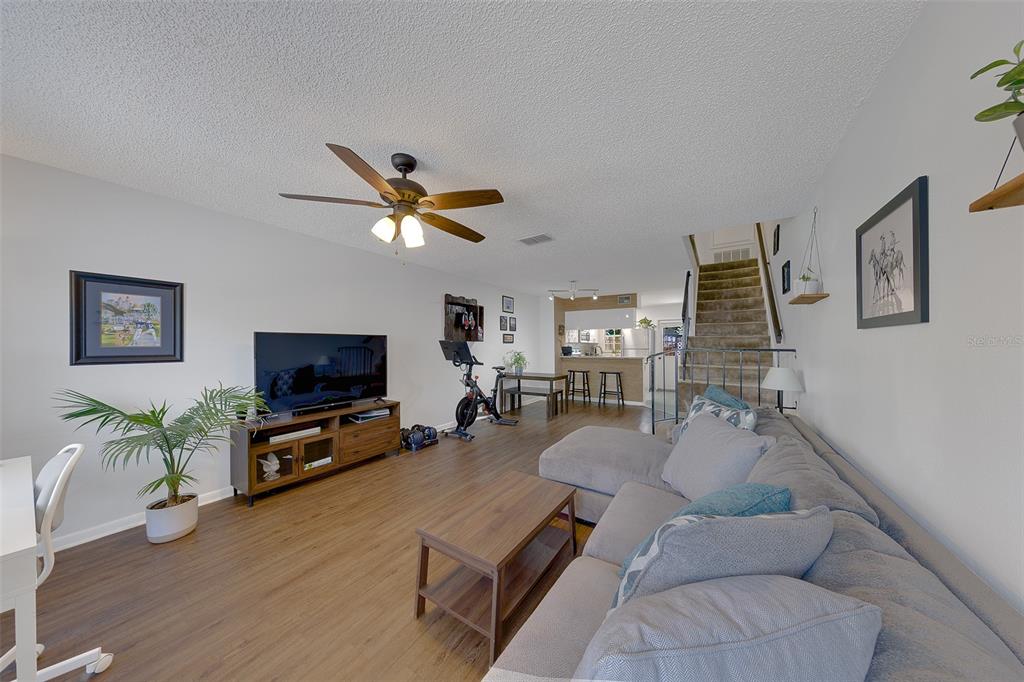 A living room with wood-look flooring, a grey sectional sofa, and a staircase — 3315 W WYOMING CIRCLE UNIT 3315, TAMPA, FL