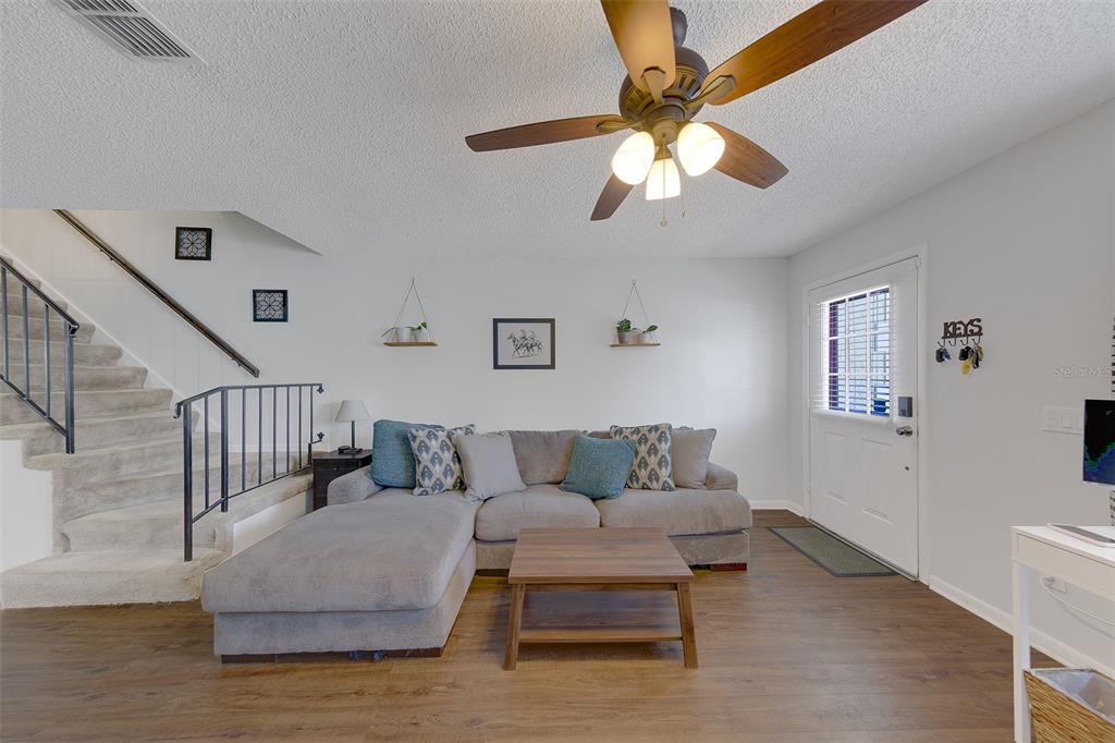 A living room features a grey sectional sofa, wood coffee table, and stairs with railings — 3315 W WYOMING CIRCLE UNIT 3315, TAMPA, FL